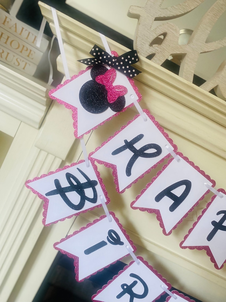 May include: Pink and white banner with black letters spelling "Happy Birthday" with a pink and black Minnie Mouse head at the top.