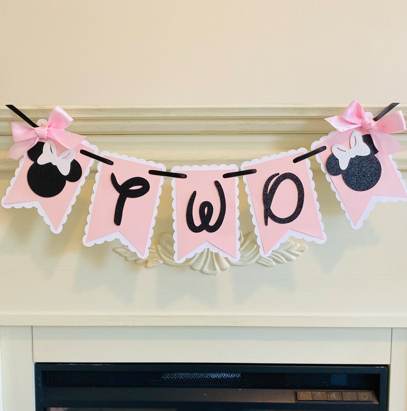 May include: Pink and black banner with the word "TWO" in black letters and two black and pink Minnie Mouse heads on either end.