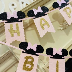 May include: Pink and black banner with gold glitter letters spelling "Happy Birthday". The banner features black mouse ears with pink bows.