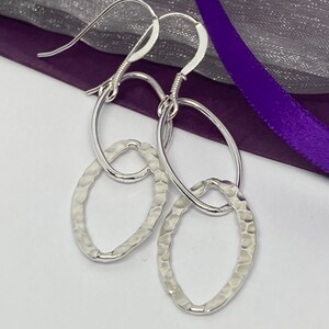 Delicate oval textured and smooth sterling silver hoops suspended on sterling silver wires.