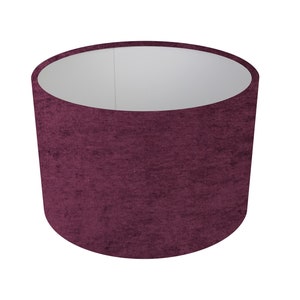 May include: A deep purple velvet lampshade with a white interior. The shade is cylindrical in shape and has a textured surface.