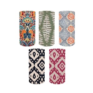 May include: Five fabric-covered cylindrical items with diverse patterns. The patterns include floral, fern-like, and geometric designs in colours like red, blue, green, and black. These could be decorative items or fabric samples.