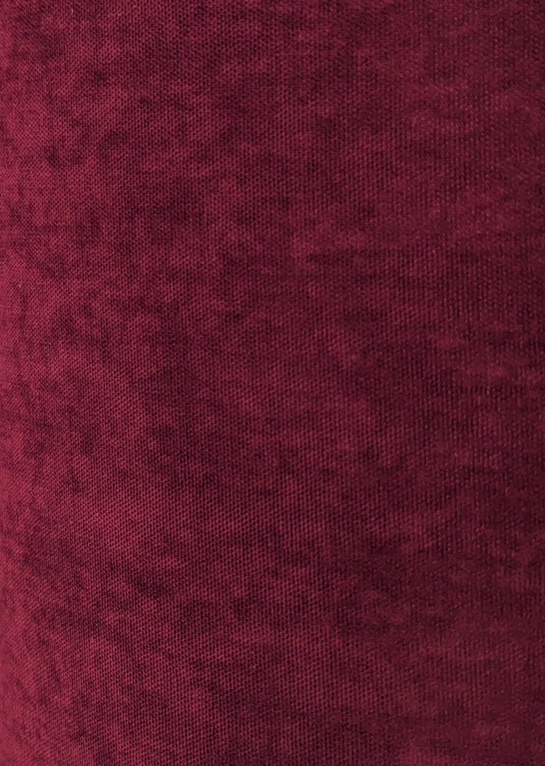 May include: Close-up of a deep burgundy fabric with a textured woven pattern.