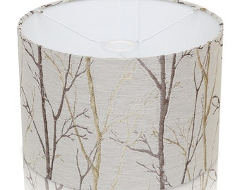 May include: A white lampshade with a beige and gold fabric pattern of branches. The fabric has a subtle texture.