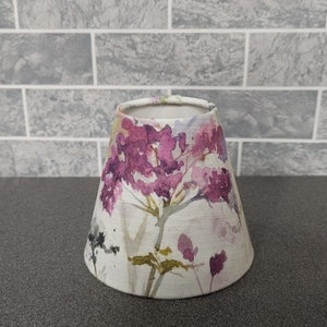 May include: A white lampshade with a floral pattern in shades of pink, purple, and green. The floral pattern is a watercolour style.