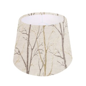 May include: A beige lampshade with a pattern of brown branches on a white background.