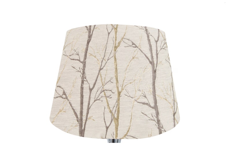 May include: A beige lampshade with a pattern of brown and gold branches.