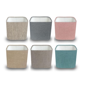 May include: Six square fabric storage bins in various colours: beige, grey, pink, tan, brown, and teal. Each bin has a white interior and a textured exterior. The bins are arranged in two rows of three against a white background.