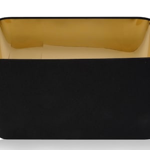 May include: A black lampshade with a gold interior. The lampshade is rectangular in shape and has a smooth, fabric-like texture.