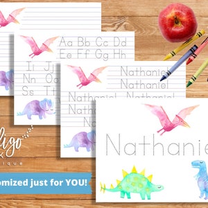 May include: Printable dinosaur themed tracing worksheets for kids. The worksheets feature a pink pterodactyl, a purple triceratops, and a green stegosaurus. The worksheets include tracing lines for letters and the name "Nathaniel".