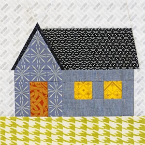 May include: A patchwork house block with a blue body, black roof, and patterned details. The house features two yellow windows, a red-orange door, and a light blue roof with a starburst pattern. The background has a white and grey pattern.