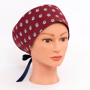 May include: A burgundy scrub cap with a white and blue pattern of small eyeglasses. The cap has a navy blue ribbon tie.
