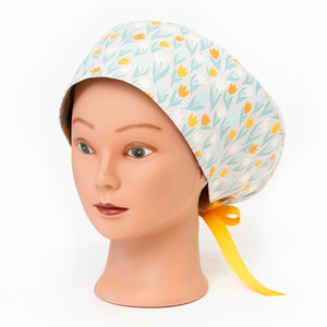 May include: A light blue and white patterned surgical scrub cap with yellow flowers. The cap has a yellow ribbon tie.