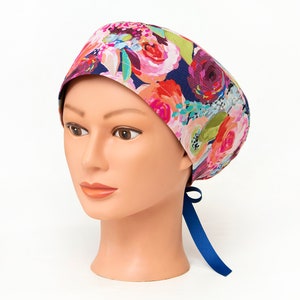 May include: A blue scrub hat with a floral print featuring pink, red, and green flowers. The hat has a blue tie at the back.