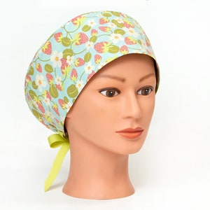 May include: A light blue surgical scrub hat with a strawberry and flower pattern. The hat has a green tie.