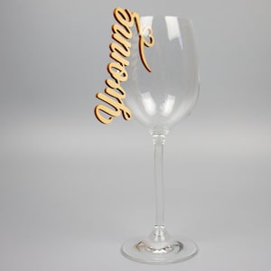 May include: A wooden wine glass charm with the name "Yvonne" written in cursive.