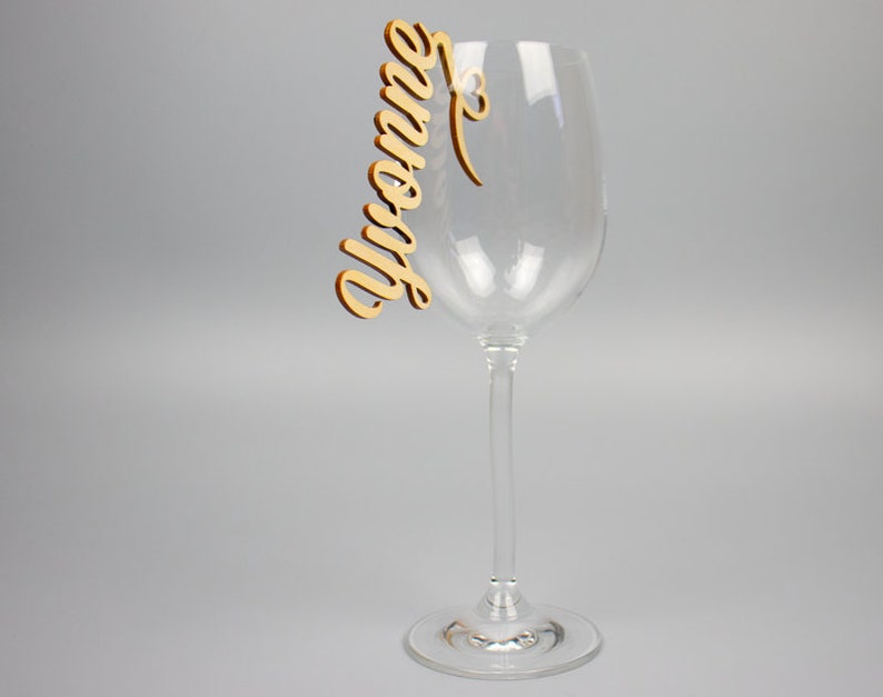 May include: A wooden wine glass charm with the name "Yvonne" written in cursive.
