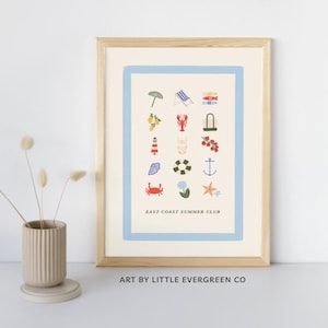 Puede incluir: Una impresión enmarcada con un borde azul claro presenta ilustraciones con temas de verano. La impresión incluye imágenes de una sombrilla, limones, una langosta, un faro, un cangrejo y un ancla. El texto "EAST COAST SUMMER CLUB" está en la parte inferior.