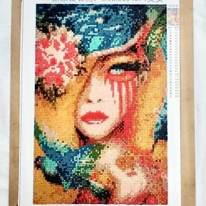 May include: A colorful diamond painting of a woman's face with a flower and birds. The painting is titled "CANX3004374 Beauty".