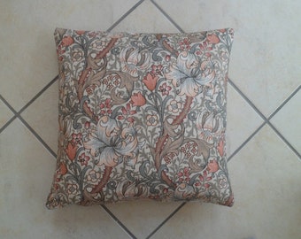 May include: A decorative pillow with a floral pattern in shades of brown, beige, and pink. The pattern features stylized lilies and leaves.