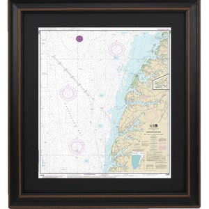 May include: A nautical chart of Chesapeake Bay, showing the waterways and islands of the bay. The chart is framed in a black frame with a brown mat.