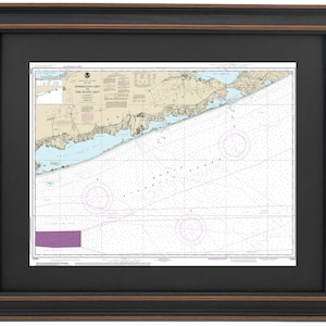 May include: A nautical chart of the Shinnecock Inlet to Fire Island Light area, printed on white paper with blue and black lines. The chart is framed in a black frame with a brown inner border.