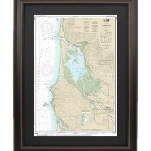 May include: A nautical chart of Tillamook Bay, Oregon, with soundings in feet. The chart shows the coastline, waterways, and surrounding land features. It includes details like depths, buoys, and navigational aids.