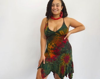 Può includere: Abito tie-dye verde, rosso e arancione. L'abito ha un collo all'americana e un orlo asimmetrico. La modella indossa una collana e orecchini di perline rosse e sandali neri. L'abito è lungo circa 100 cm.