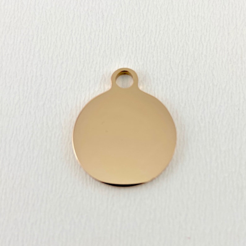 May include: A gold-colored round metal tag with a hole at the top for attaching a chain or string.