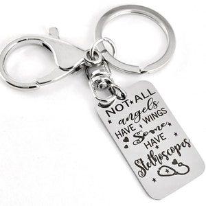 May include: Silver keychain with a silver lobster clasp and a rectangular tag that reads "NOT ALL angels HAVE WINGS Some HAVE Stethoscopes".