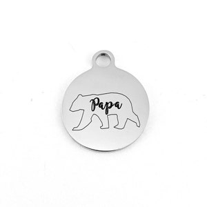 May include: Silver round charm with a bear silhouette and the word "Papa" engraved on it.