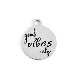 May include: Silver charm with the text "good vibes only" in black lettering.