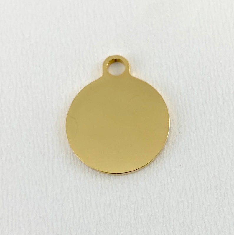 May include: A gold-colored round metal tag with a hole at the top for attaching to a necklace or keychain.