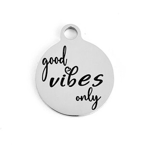 May include: Silver charm with the text "good vibes only" in black lettering.
