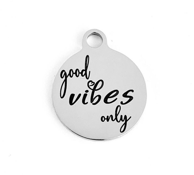 May include: Silver charm with the text "good vibes only" in black lettering.