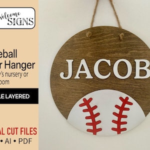 May include: A wooden round door hanger with the name "JACOB" in white letters and a white baseball with red stitching on a brown background.