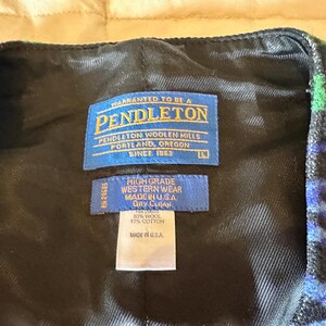 Puede incluir: Primer plano de un chaleco con estampado negro, azul y verde. El forro interior es negro. El chaleco tiene una etiqueta Pendleton con el texto "Pendleton Woolen Mills, Portland, Oregon, Since 1863". El chaleco est&aacute; hecho en los EE. UU.