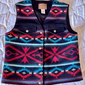 May include: A black Pendleton wool vest with a geometric pattern in red, blue, and yellow. The vest has a button closure and two flap pockets.