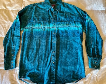 May include: A long-sleeved button-down shirt in shades of teal and turquoise, featuring a geometric pattern. The shirt has two chest pockets and a classic collar. The fabric appears to be a lightweight material.