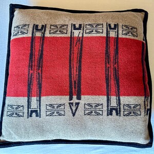 Peut inclure: Coussin carr&eacute; avec un motif beige et rouge. Le coussin pr&eacute;sente une bande rouge centrale avec des lignes verticales noires et des formes g&eacute;om&eacute;triques. Il est bord&eacute; d'une bordure noire.