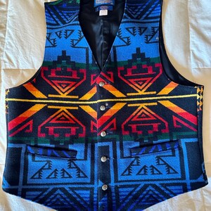 Puede incluir: Un chaleco colorido con un patr&oacute;n geom&eacute;trico en azul, negro, rojo, amarillo y verde. El chaleco tiene cuello en V, cuatro botones plateados y dos bolsillos delanteros. El interior es negro.