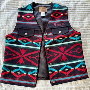May include: A black wool vest with a geometric pattern in red, blue, and yellow. The vest has a black satin lining and a patch on the left side that says "Vermilion Park".