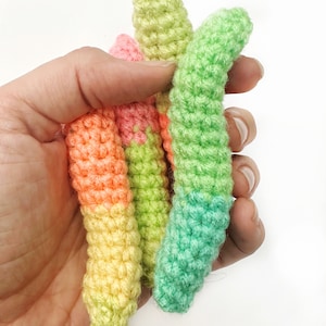 May include: Four crocheted worm toys in different colors: green, yellow, orange, and pink. The worms are made with a textured stitch and are about 6 inches long.