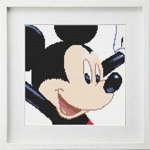 Peut inclure: Un gros plan sur le visage de Mickey Mouse, avec ses oreilles noires caractéristiques, ses grands yeux et un large sourire. Il regarde vers la droite, et son short rouge est visible en bas de l'image.
