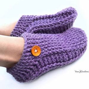 Op de afbeelding: Paarse gebreide pantoffels met een houten knoop. De sokken zijn zacht en comfortabel, perfect om je voeten warm te houden in de winter.