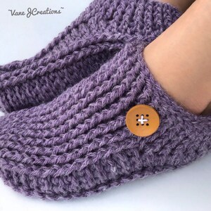 Op de afbeelding: Paarse gebreide pantoffels met een houten knoop aan de bovenkant. De pantoffels zijn zacht en comfortabel, perfect om je voeten warm te houden in de winter.