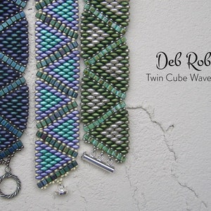 May include: Three beaded bracelets in shades of blue, green, and silver. The bracelets are made with small, square beads and have a wave-like pattern. The bracelets are labeled "Deb Roberta Twin Cube Wave Band".