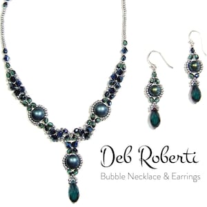 Könnte beinhalten: Eine silberne Halskette und passende Ohrringe mit dunkelgrünen und blauen Perlen. Die Halskette hat einen Tropfenanhänger und die Ohrringe sind Ohrhänger. Der Schmuck ist mit "Deb Roberti Bubble Necklace & Earrings" beschriftet.