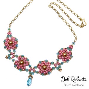 Peut inclure: Un collier en chaîne dorée avec un motif de perles roses et bleues, composé de trois motifs en forme de fleur et d'un pendentif en forme de larme. Le collier est étiqueté "Deb Roberti Bistro Necklace".