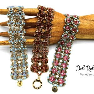 Könnte beinhalten: Drei Perlenarmbänder in verschiedenen Farben, darunter Blau, Braun und Pink, mit goldenen Akzenten. Die Armbänder werden auf einem Holzhandmodell präsentiert. Der Text "Deb Roberti Venetian Cuff" ist unterhalb der Armbänder sichtbar.